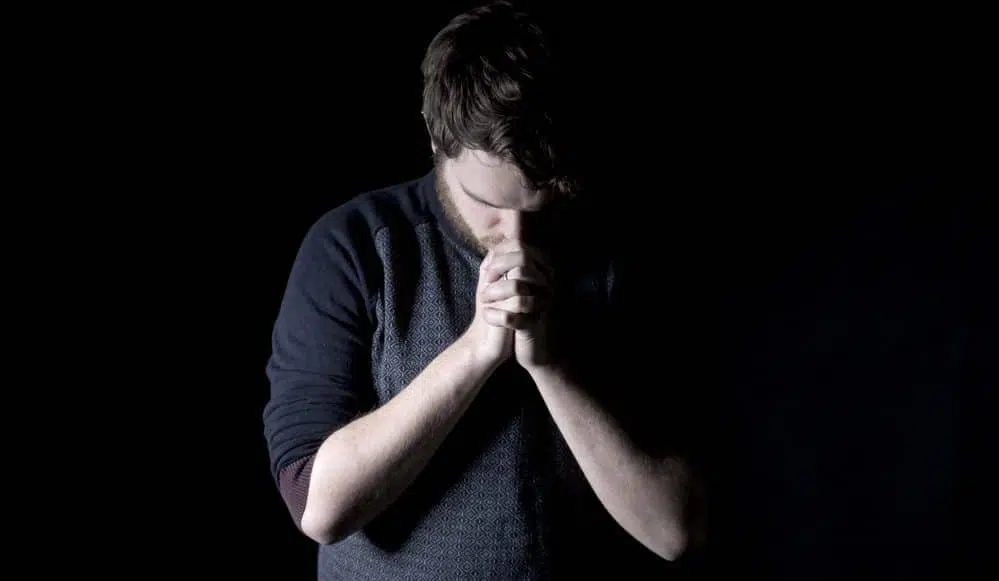 man praying in dark