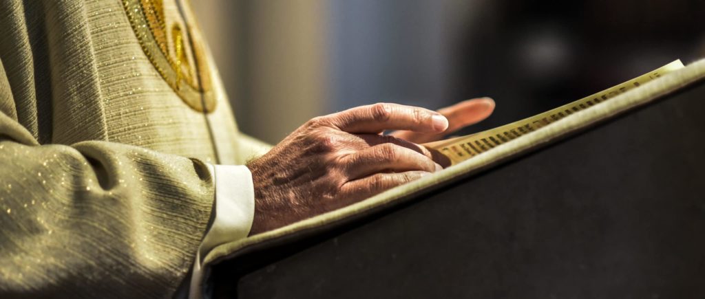 Hands of catholic priest reading a bible, priest at pulpit