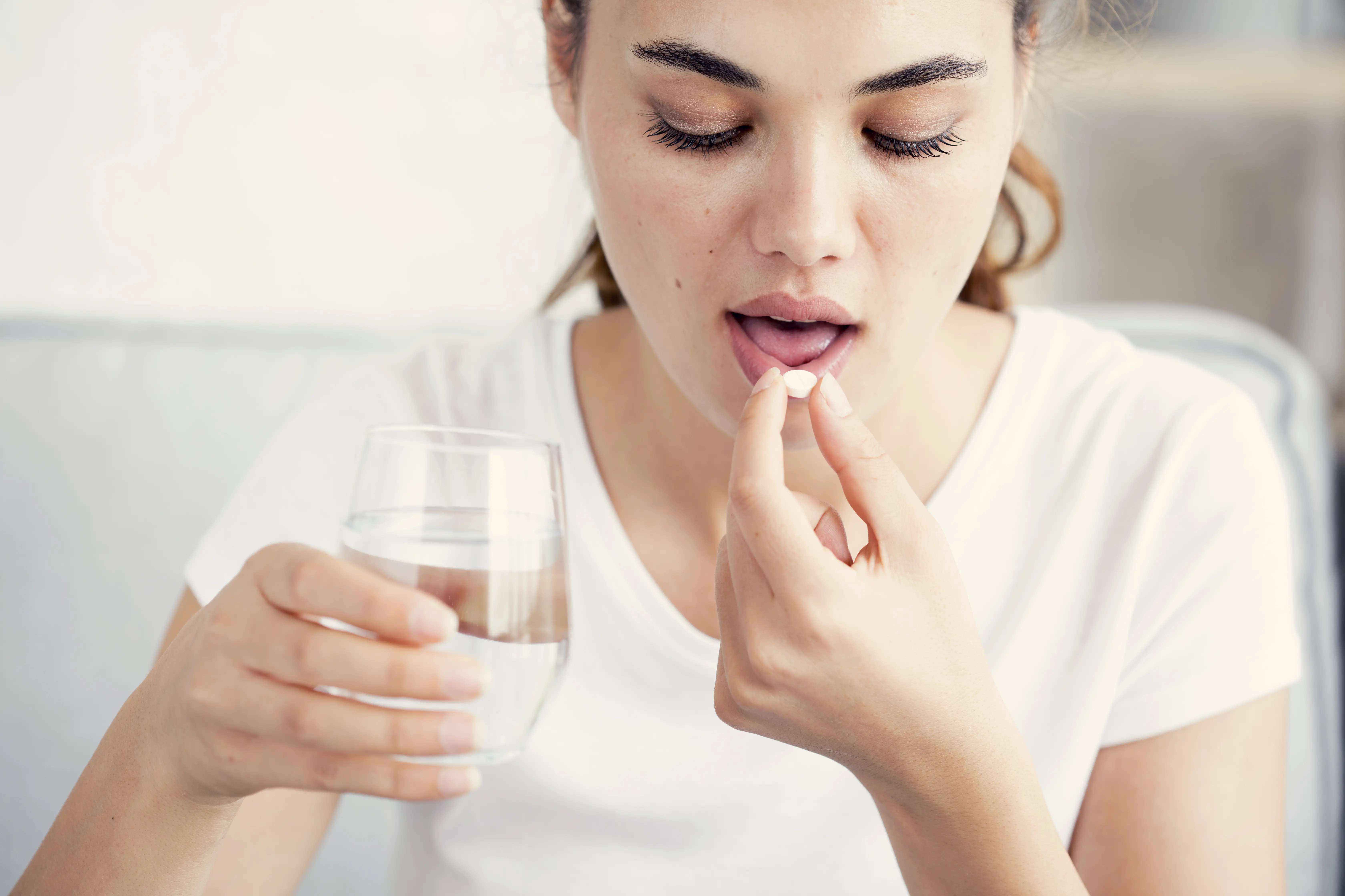 young woman swallowing birth control pill