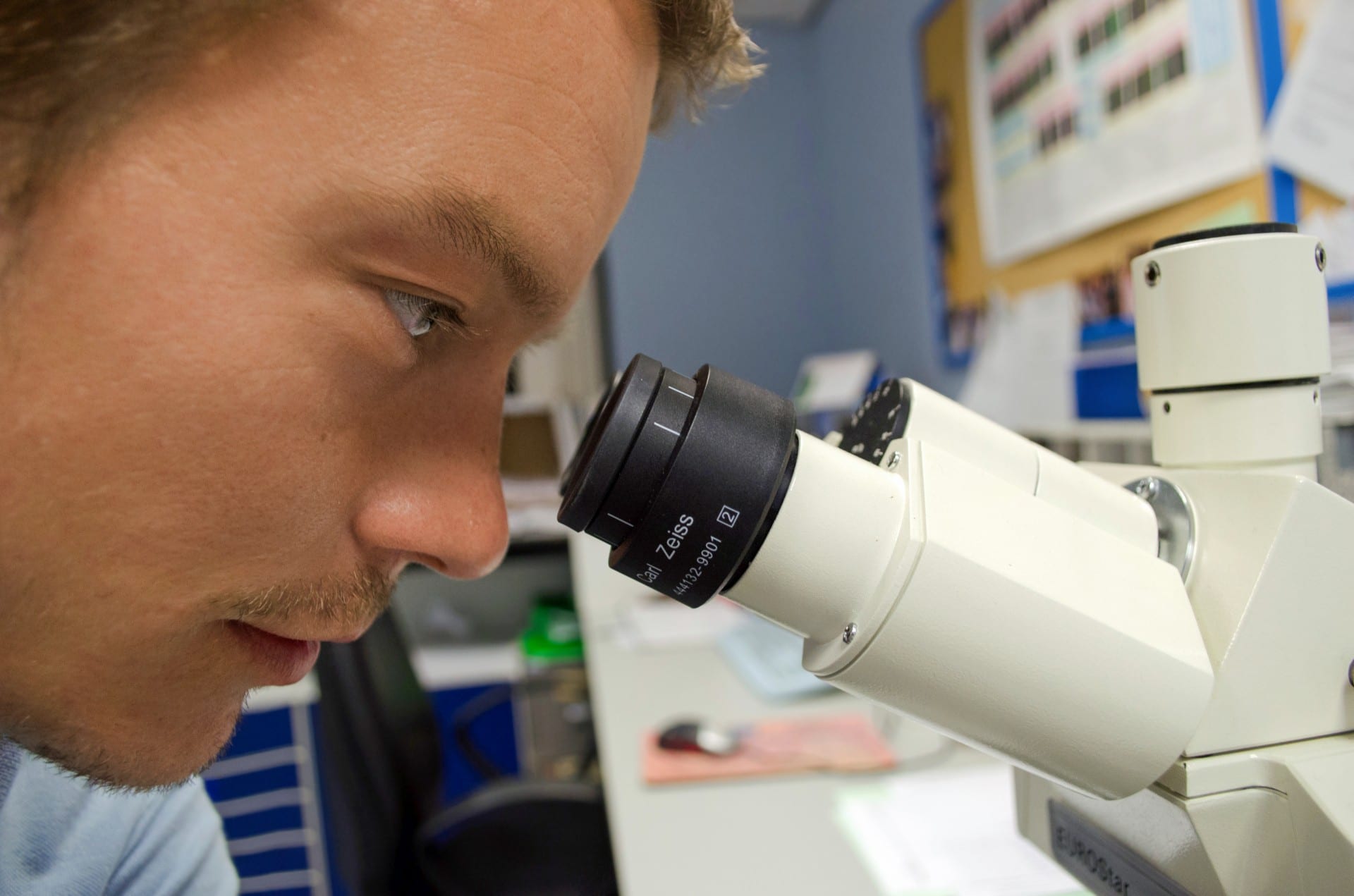 male scientist looking through microscope