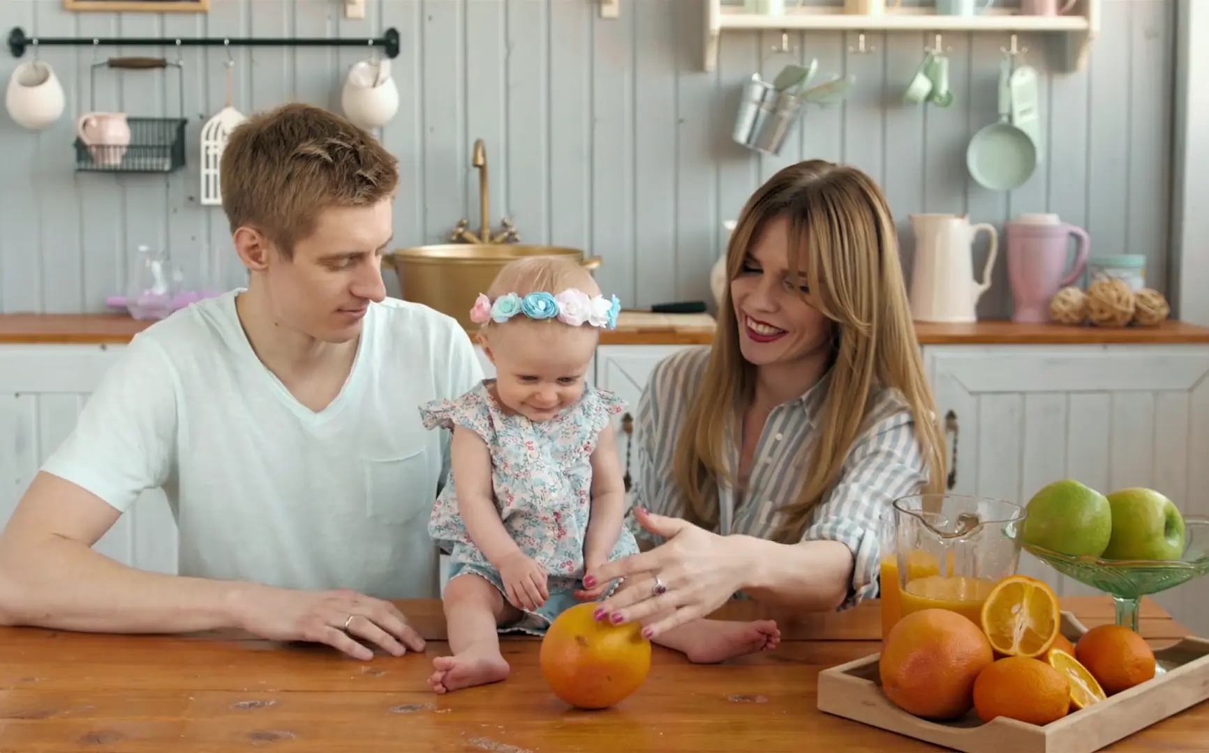 mother and father with baby holding oranges