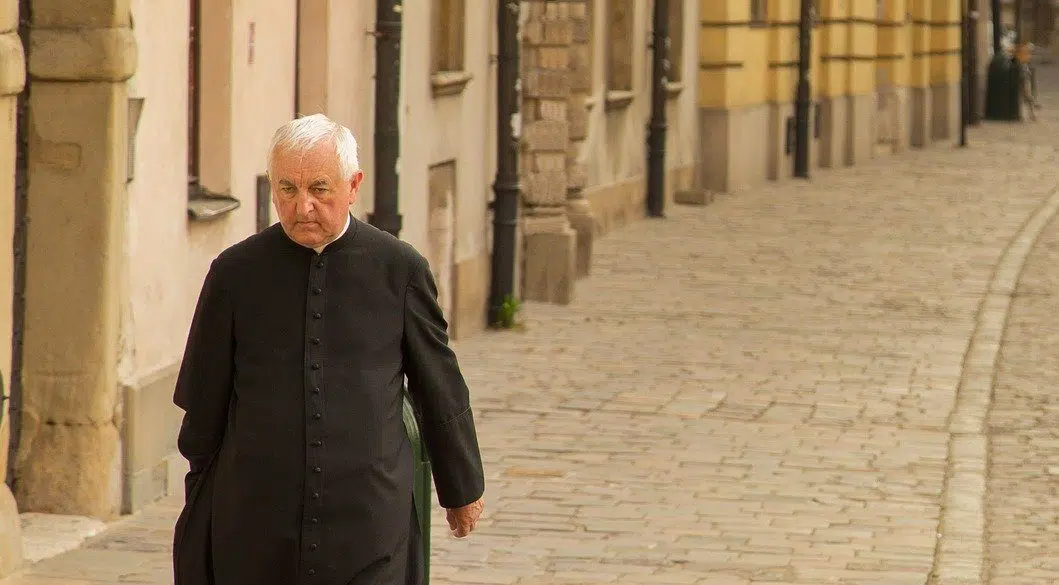 elderly priest walking in streets