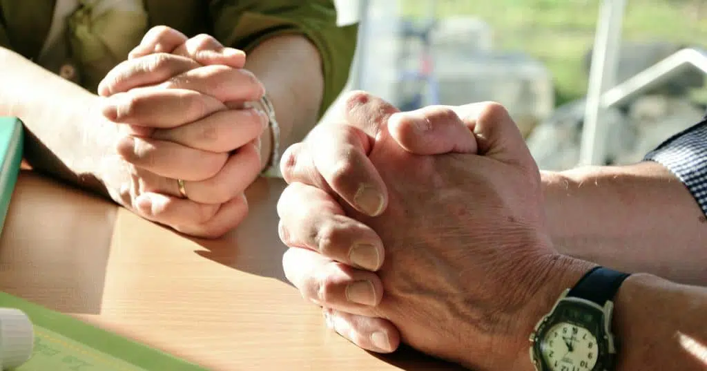 married couples hands folded praying