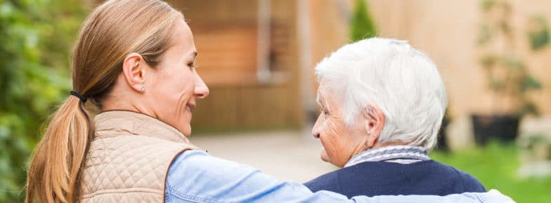 Young carer walking with the elderly woman in the park