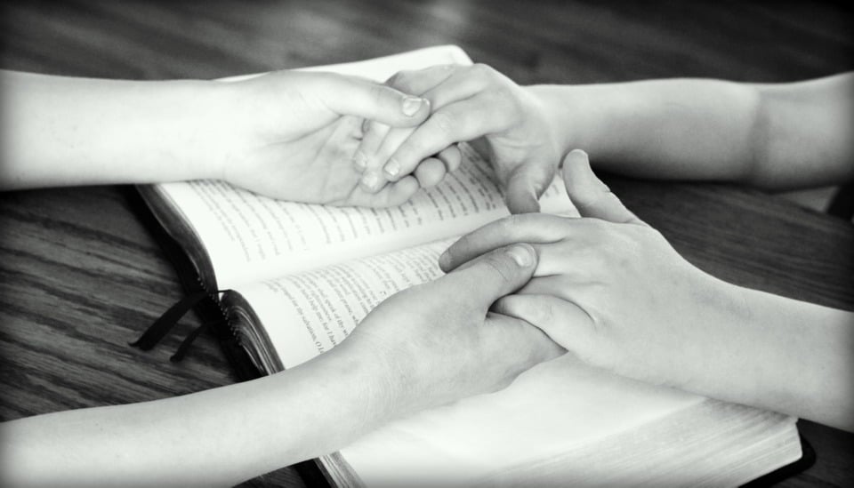 couple holding hands over bible