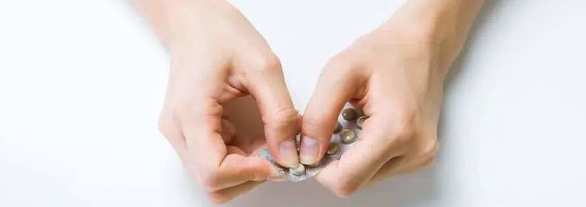 woman taking pill from packet