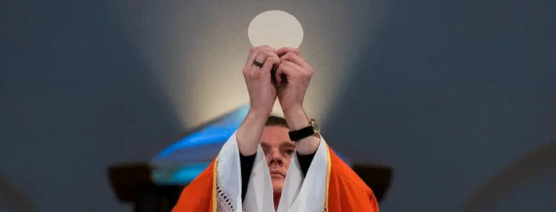 A Catholic priest consecrating Holy Communion. Photo by Josh Applegate via Unsplash.