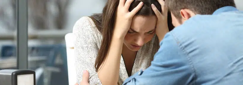 Male comforting to a sad depressed female who needs help in a coffee shop. Break up or best friend concept