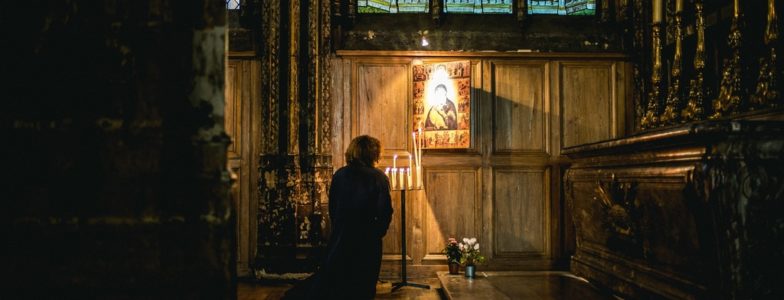 woman praying before image in church
