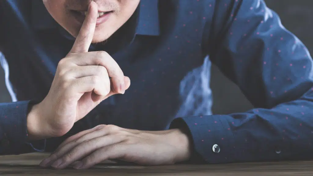 concept of secrecy, man with finger over mouth