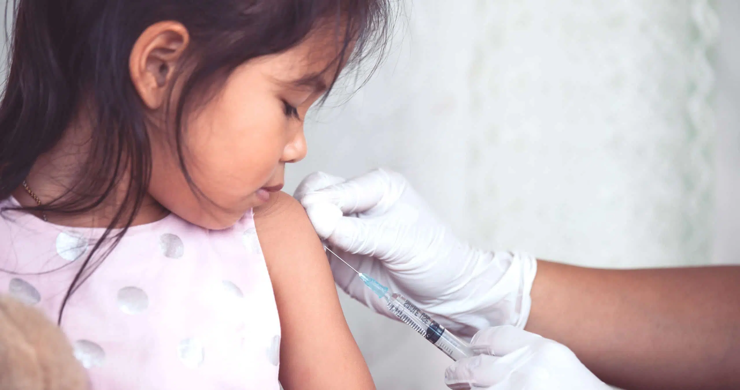 Doctor injecting vaccination in arm of asian little child girl, healthy and medical concept