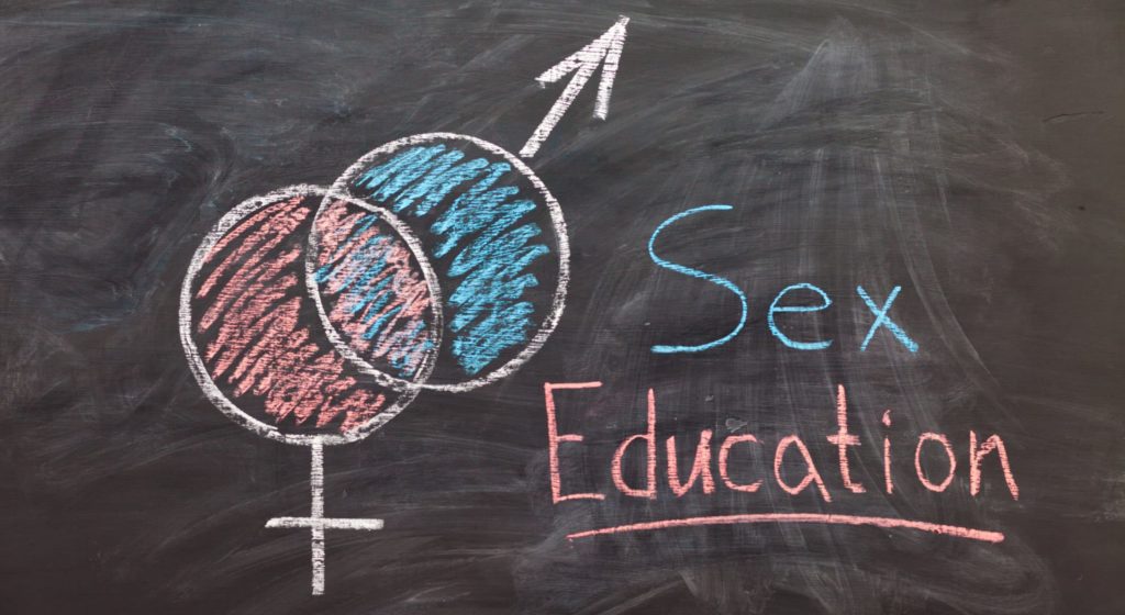 Sex Education. Male and female sex symbol on black chalkboard. Woman draws gender symbols