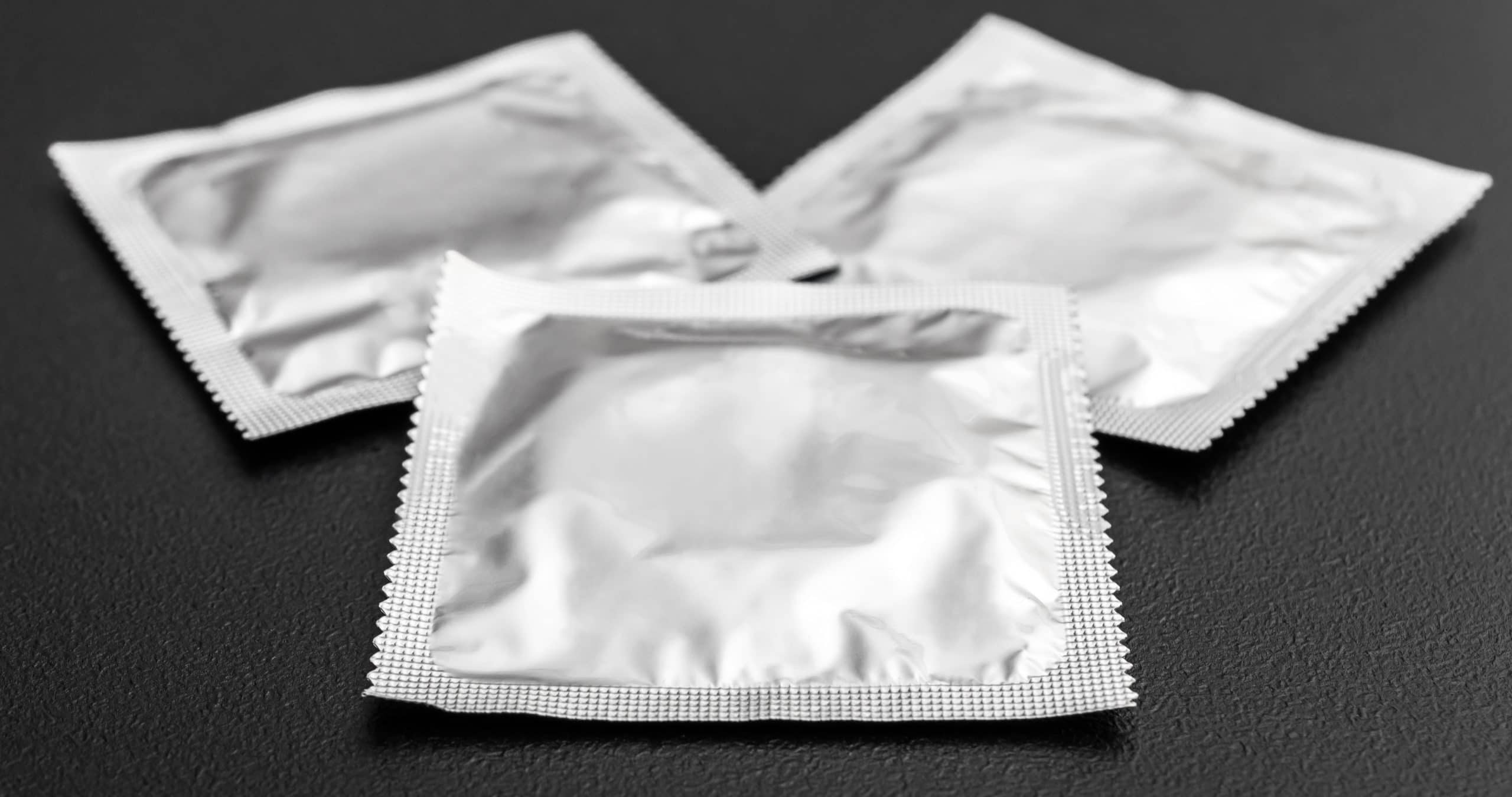 Condoms in packs on black background.