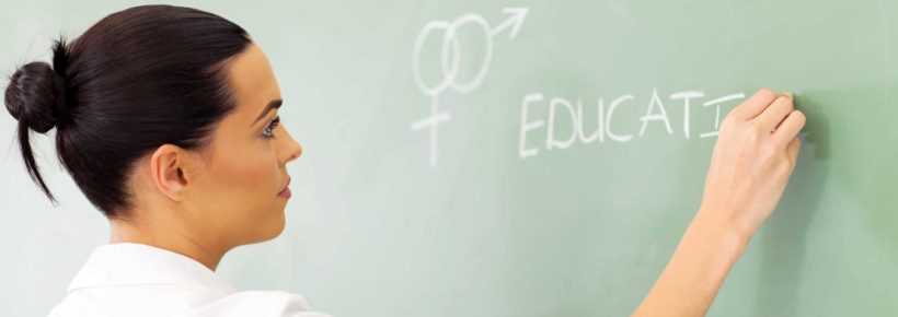 female high school educator writing sex education on chalkboard