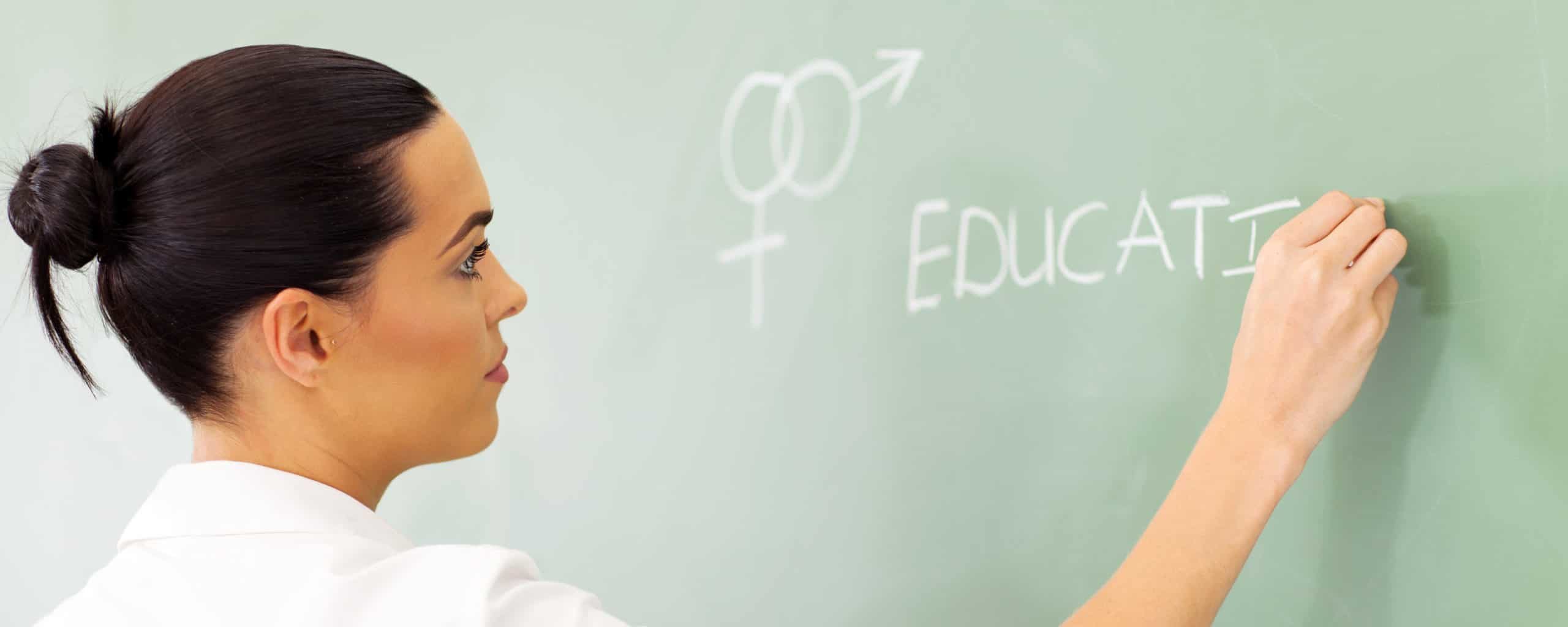 female high school educator writing sex education on chalkboard