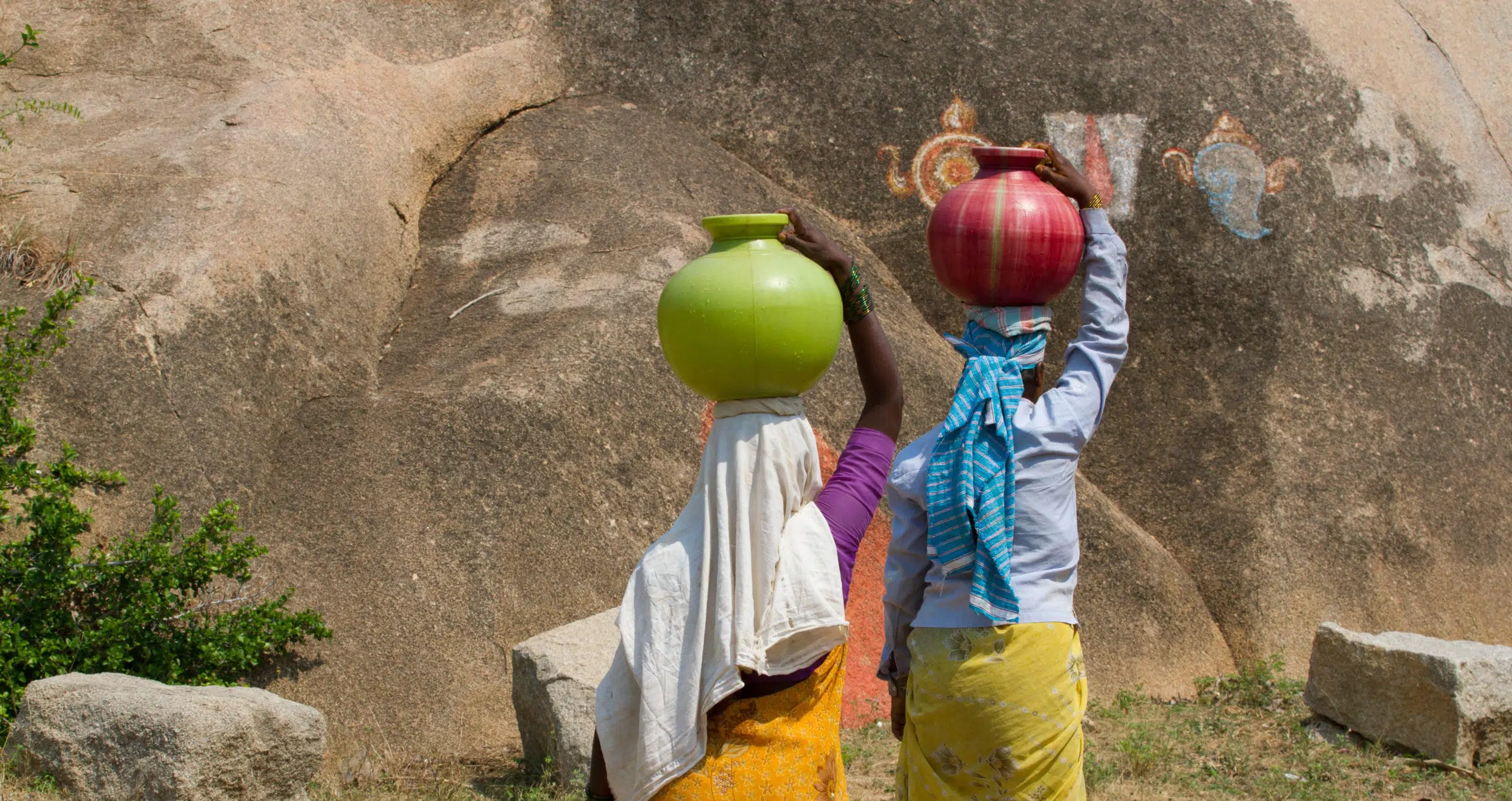 Two Indian women carry water on their heads in traditional pots