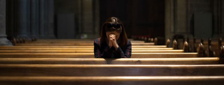 girl praying in pew in church