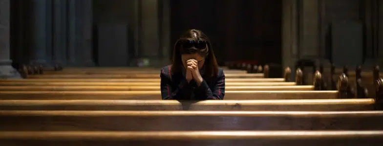 girl praying in pew in church