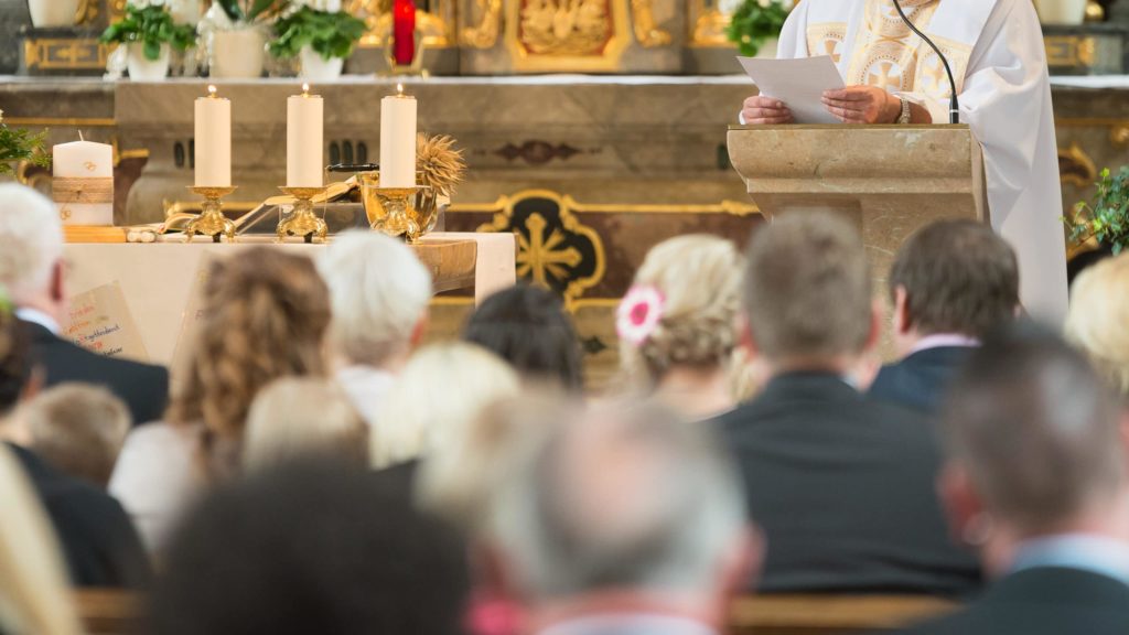 priest giving homily sermon, people listening, in church, catholic Mass