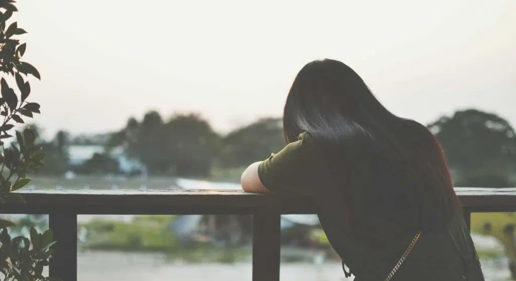 A sad woman sitting outdoors alone