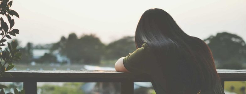 The shadow of a sad woman sitting on balcony alone