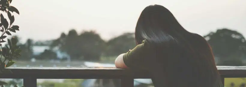 The shadow of a sad woman sitting on balcony alone