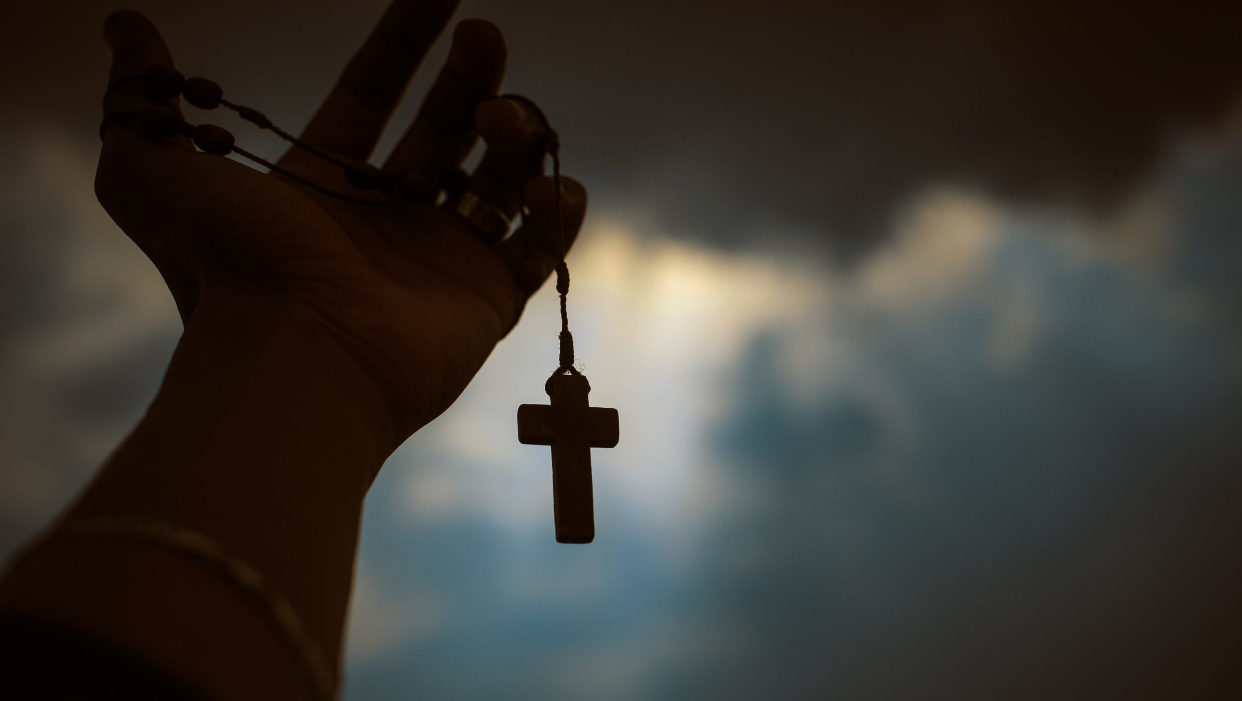 man holding up cross, rosary