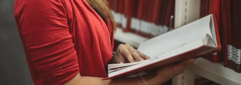 woman reading book standing in library