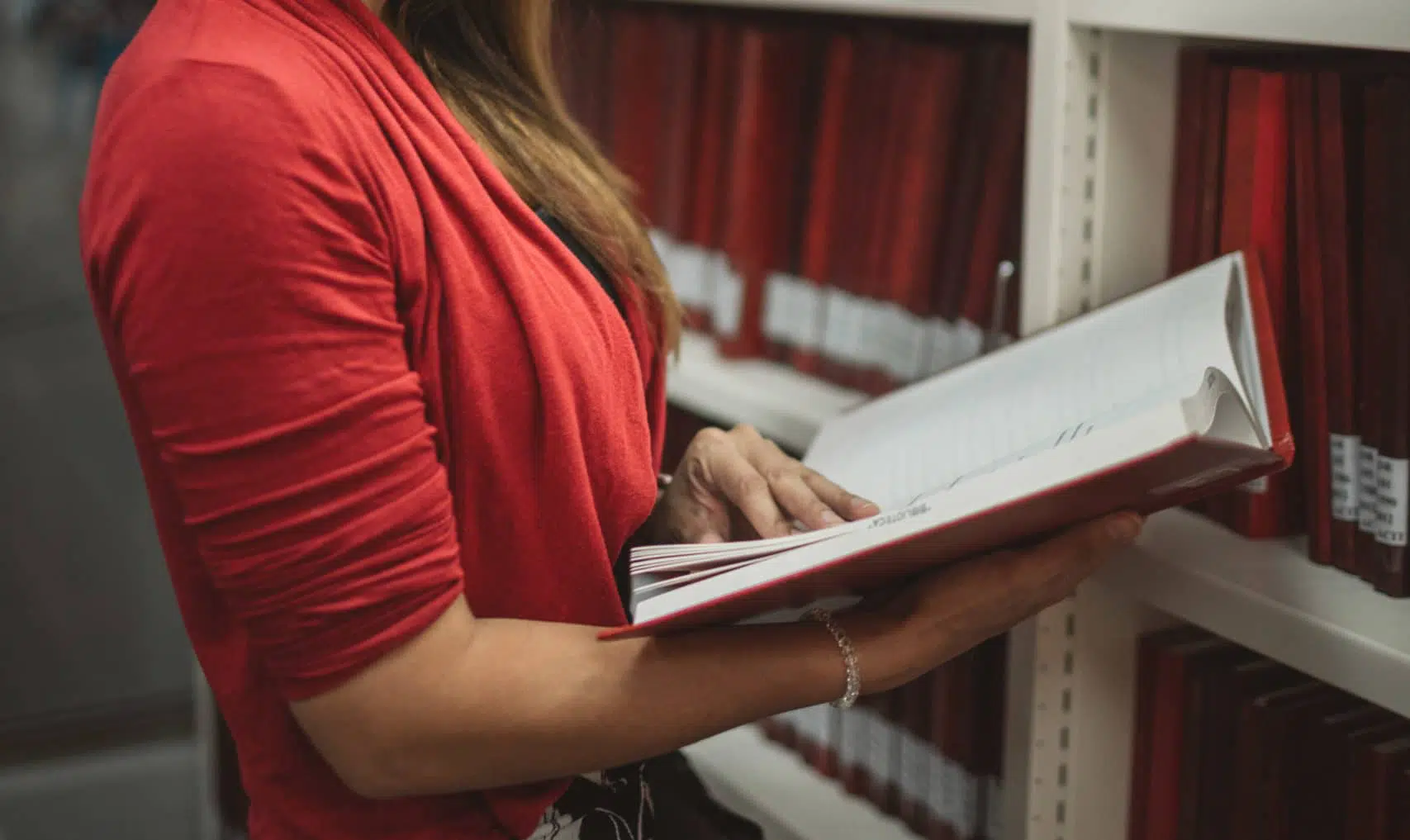 woman reading book standing in library