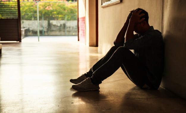 man head in hands sitting in hallway