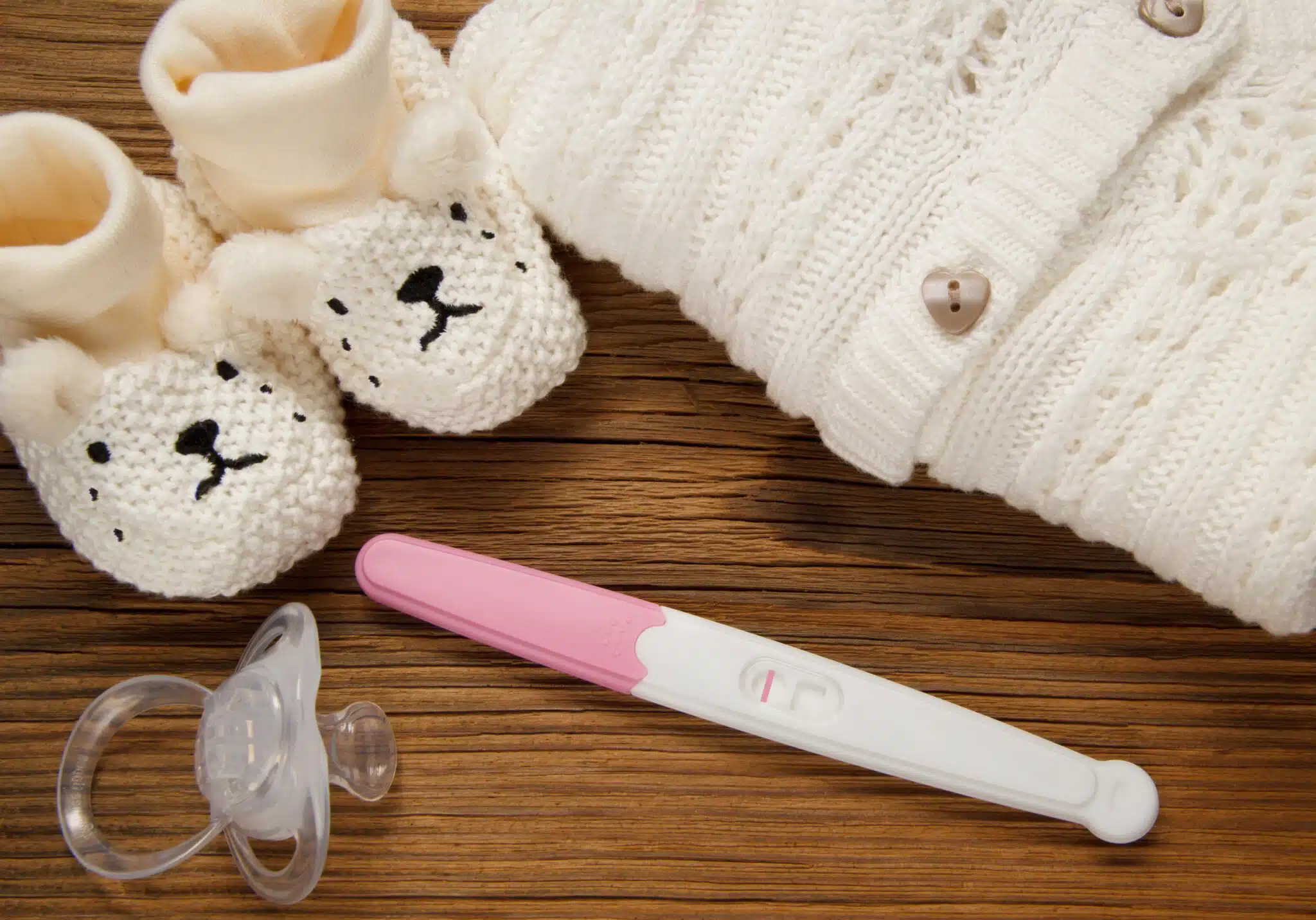negative pregnancy test next to baby clothes