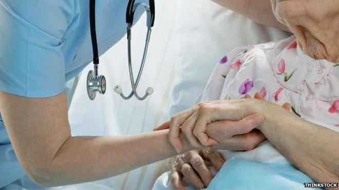 doctor with a stethoscope comforting an elderly female patient