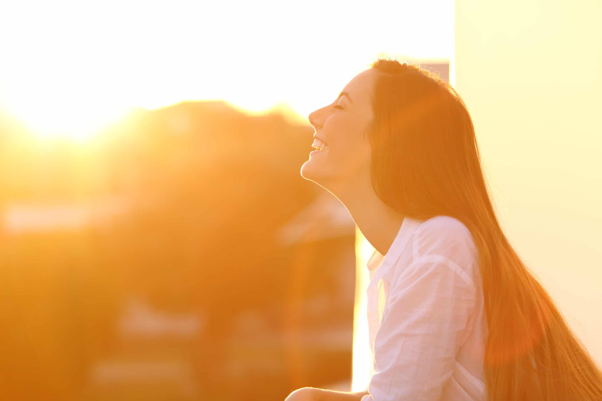 Side view portrait of a happy woman breathing deep fresh air at sunset in a house balcony