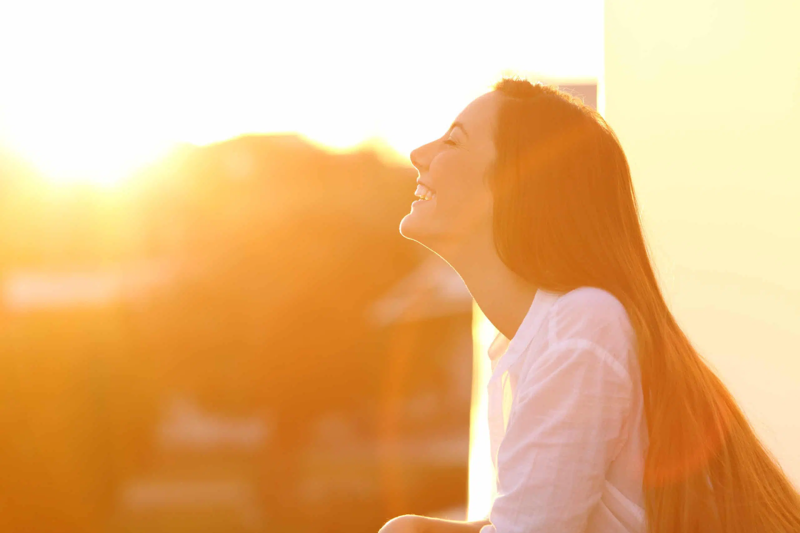 Side view portrait of a happy woman breathing deep fresh air at sunset in a house balcony