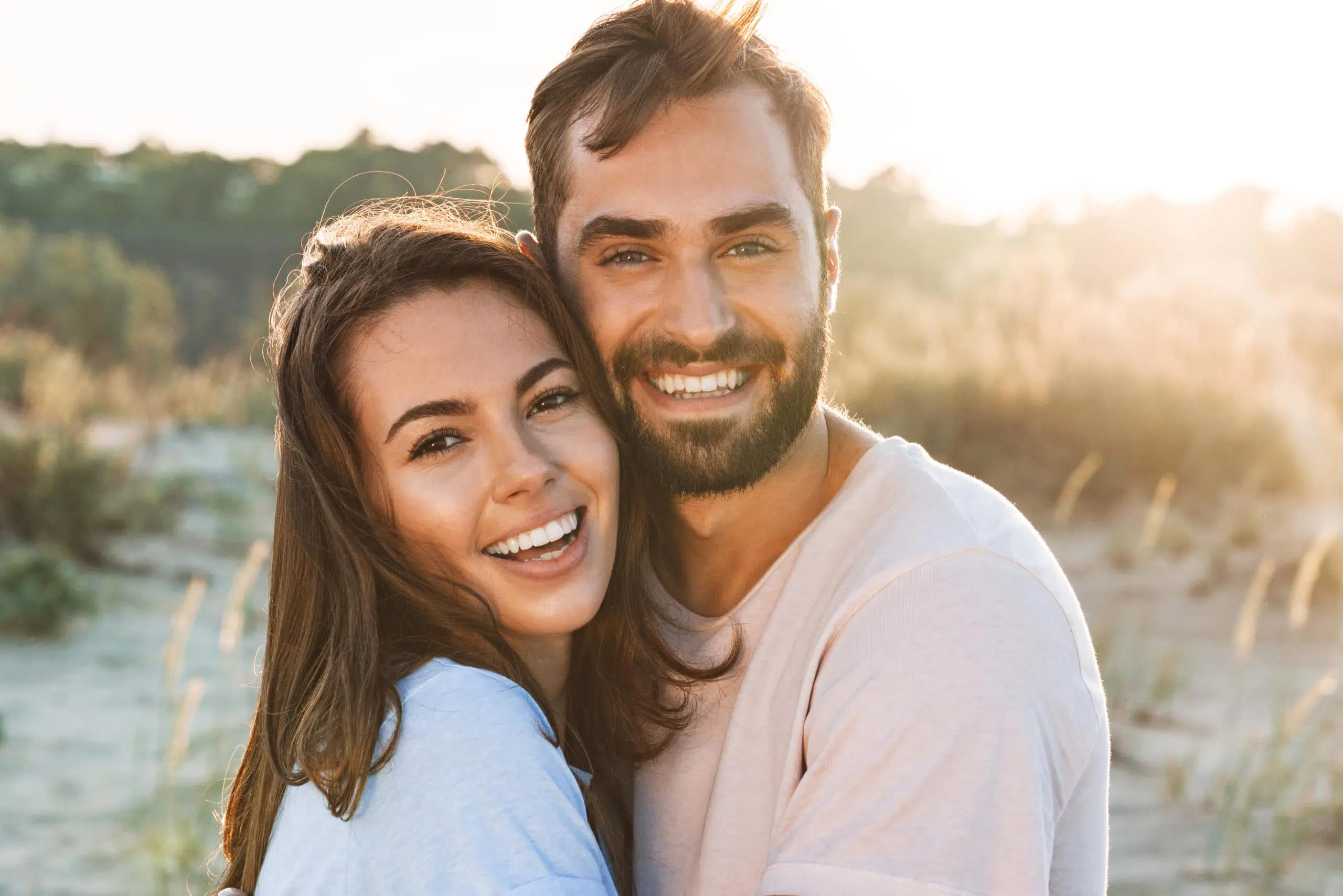 Beautiful young smiling couple spending time at the beach, hugging