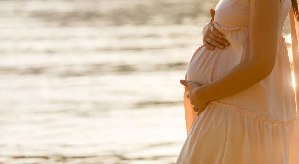 pregnant woman in the third trimester standing by the water