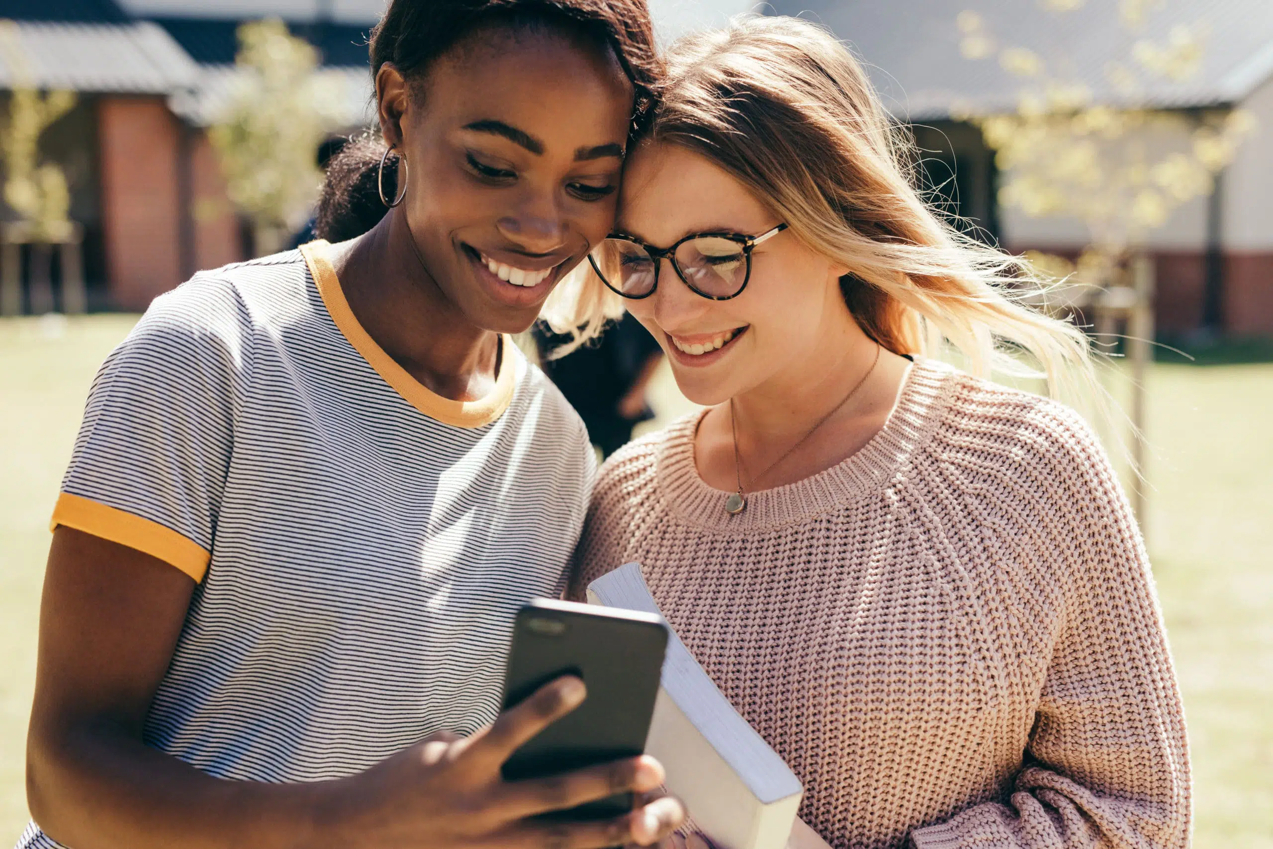 two young women looking at a phone screen and smiling