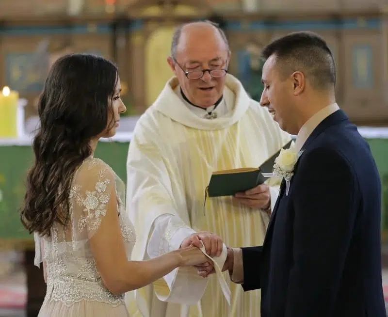 catholic priest officiating a marriage ceremony, with bride and groom facing each other