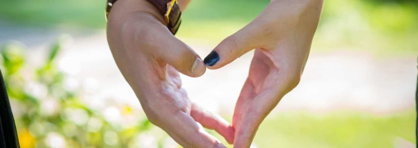 young couple's hands making a heart together