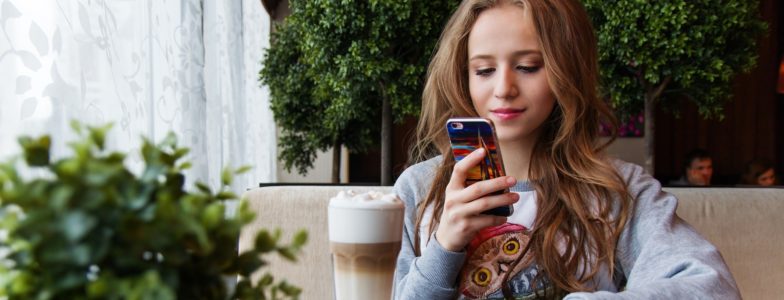 teenage girl on her phone in a coffee shop