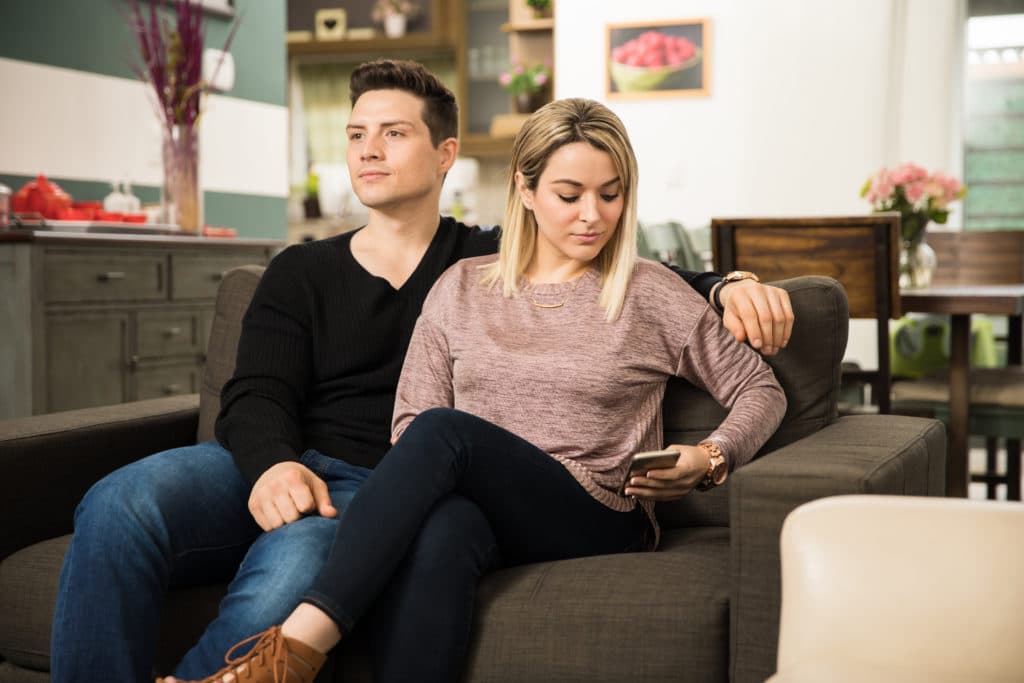 young woman on her phone ignoring the man next to her