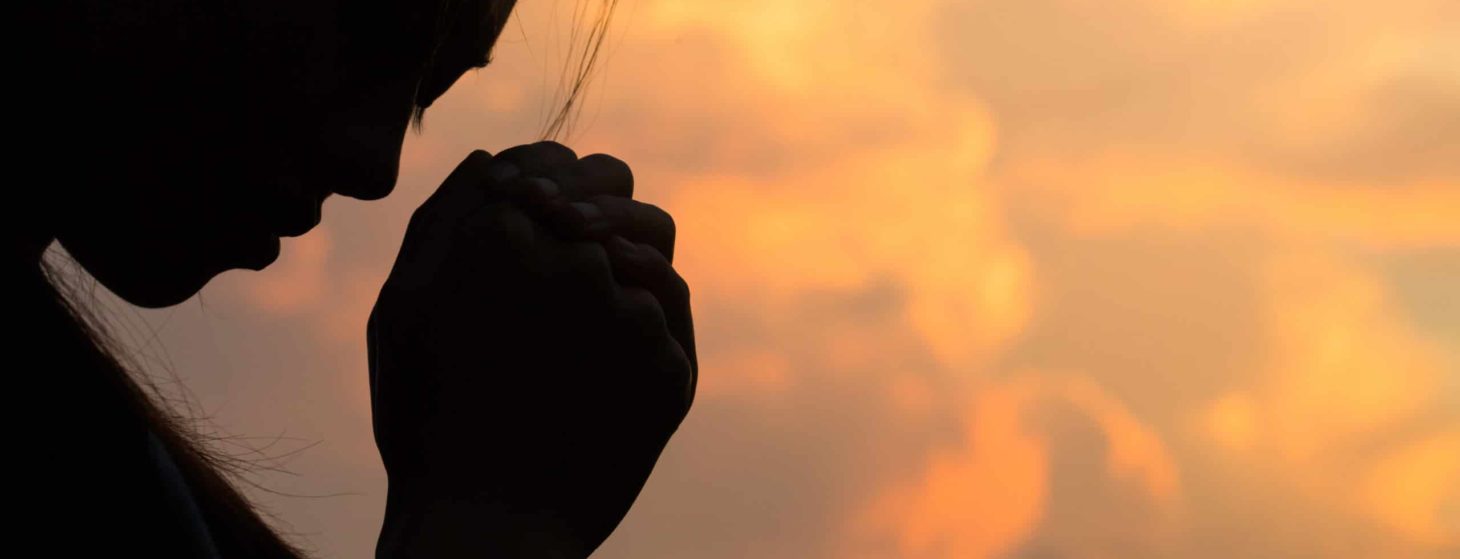 silhouette of a woman praying to God