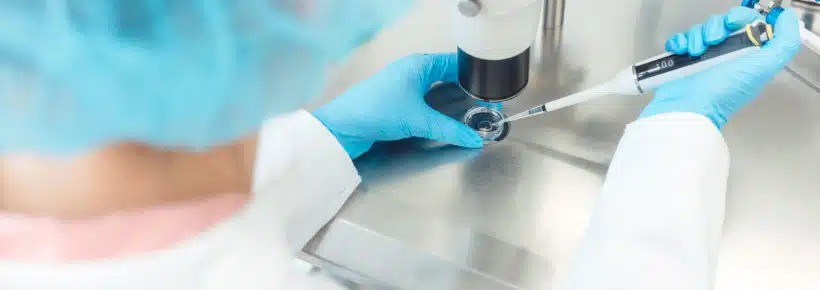 Woman scientist working with pipette in laboratory dripping egg cell in solution