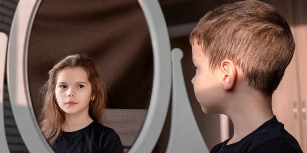 Boy with gender dysphoria looking in mirror