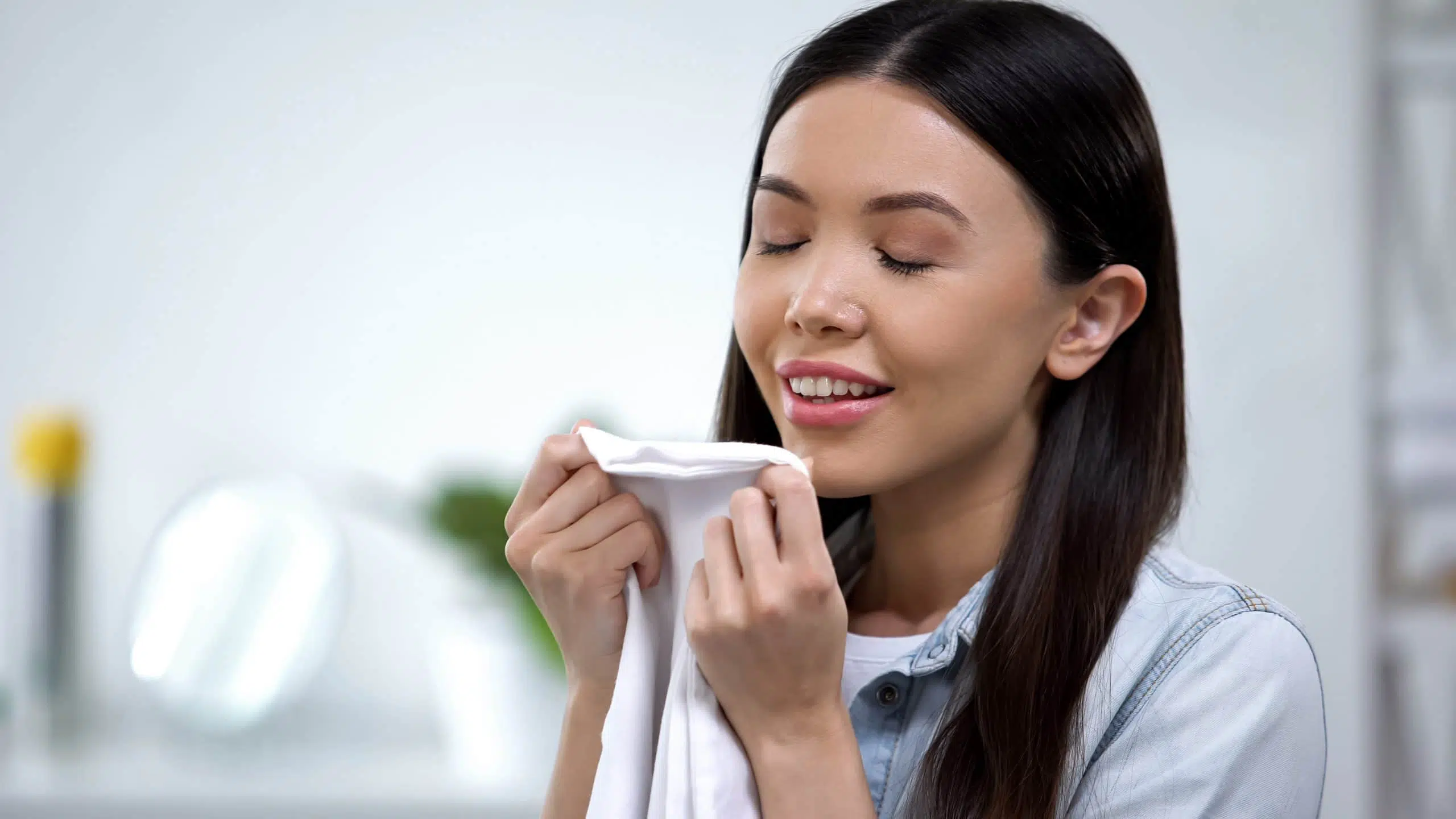 Female smelling fresh linens and smiling, enjoying fabric conditioner aroma