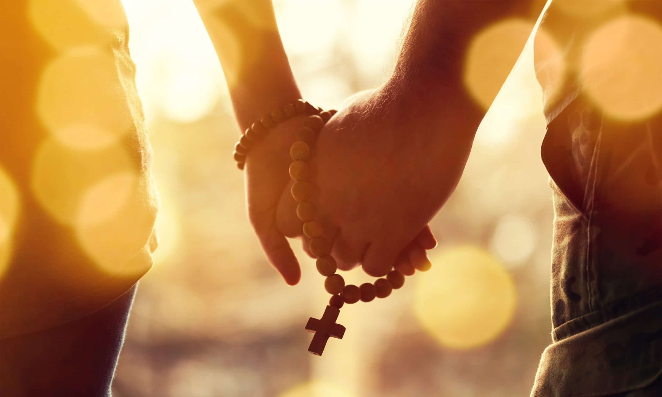 Couple praying together. Holding rosary in hand.