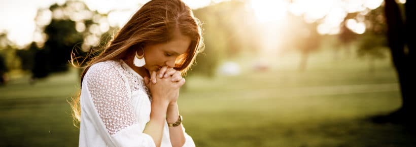 woman praying in sunny field