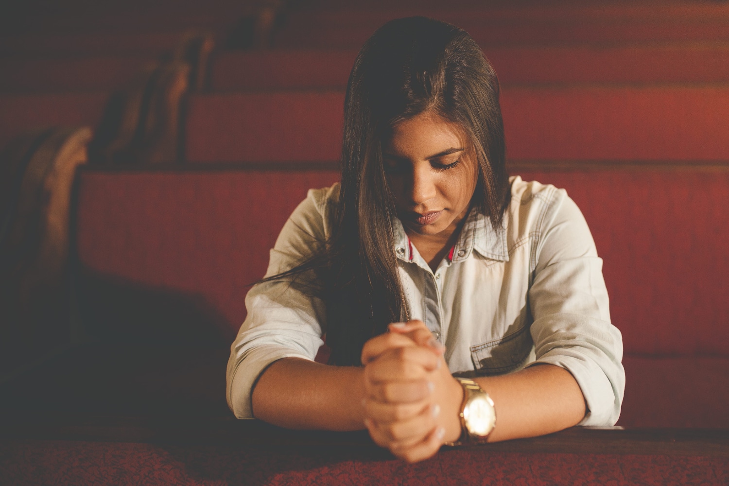 young woman praying in church pew