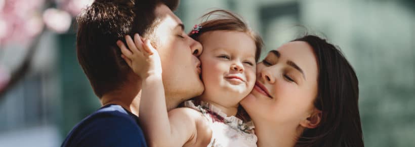 parents kissing their toddler daughter