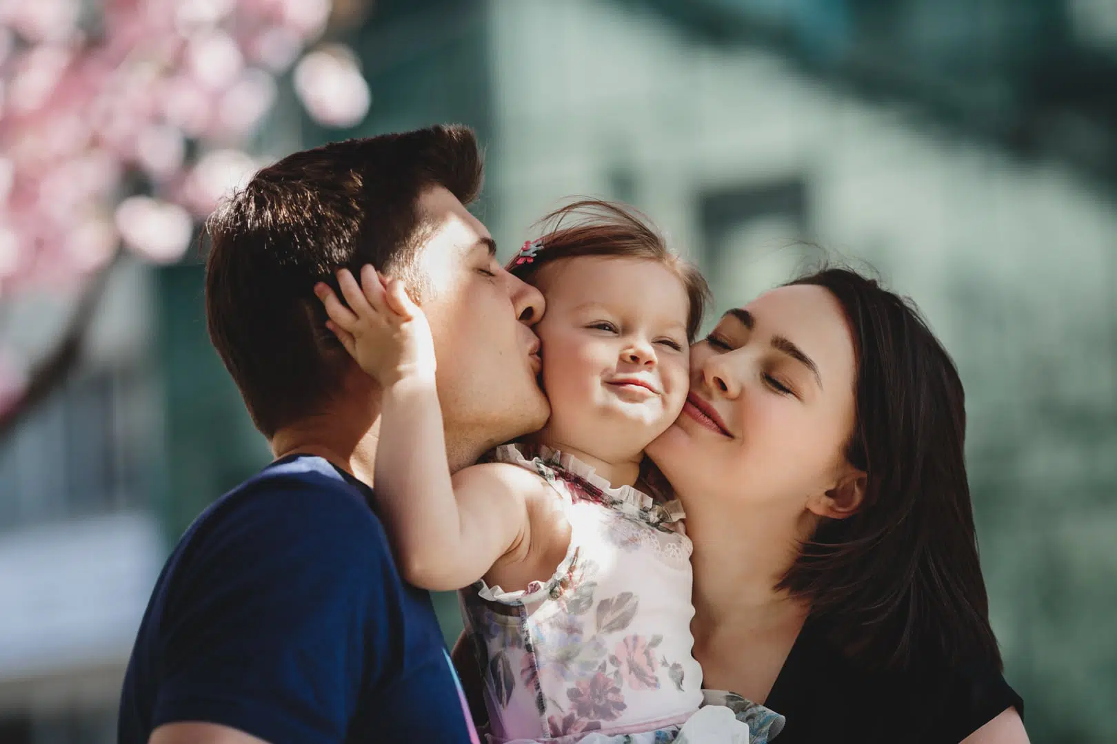 parents kissing their toddler daughter